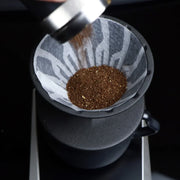 The Hario Alpha coffee dripper in matte black, featuring a minimalist cone-shaped design for manual pour-over brewing.