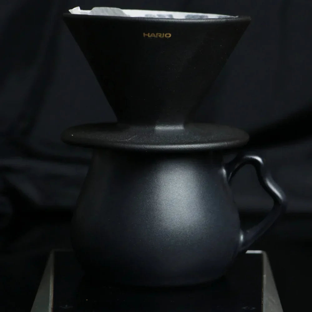 The Hario Alpha coffee dripper in matte black, featuring a minimalist cone-shaped design for manual pour-over brewing.