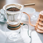Hario Drip Pot with Olive Woodneck collar and reusable cloth filter for authentic Nel drip coffee brewing.