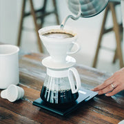 White ceramic Hario V60 pour-over set with a size 02 dripper for superior heat retention and a heatproof glass carafe.